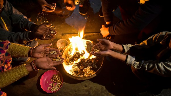Residents throw sweets, peanuts, puffed rice, and popcorn into a bonfire during the Lohri celebrations in Rajpura.