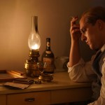 A still from the movie depicting Bonhoeffer sitting and thinking at his desk.