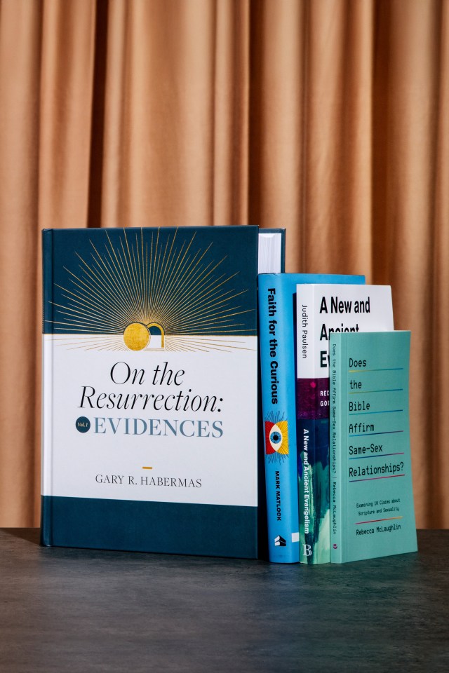 Photograph of "on the resurrection: evidences" book leaning on a stack of books against a orange curtain background