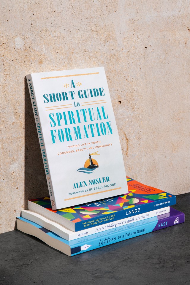 Photograph of "a short guide to spiritual formation" book on a stack of books leaning against a concrete wall