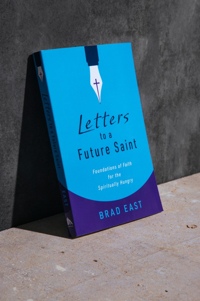 Photograph of "letters to a future saint" book leaning against a concrete wall