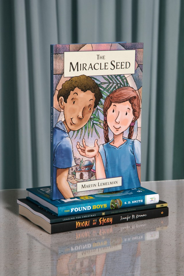 Photograph of "The Miracle Seed" book on a stack of books with a blue background