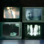 Three tv screens showing shadowy horror film images and a fourth screen showing a cross.