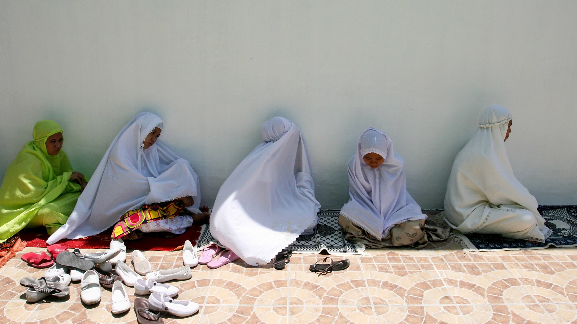 Philippine Muslim women wait for the start of their noon prayer outside a crowded Mosque.