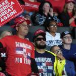 Men hold MAGA signs and wear "Dominicans for Trump" signs at a rally in Allentown, Pennsylvania.