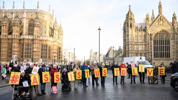 Supporters of the "Not Dead Yet" campaign, which opposes the Assisted Dying Bill, protest outside the Houses of Parliament in London, holding signs that spell out #ASSISTUSTOLIVE.