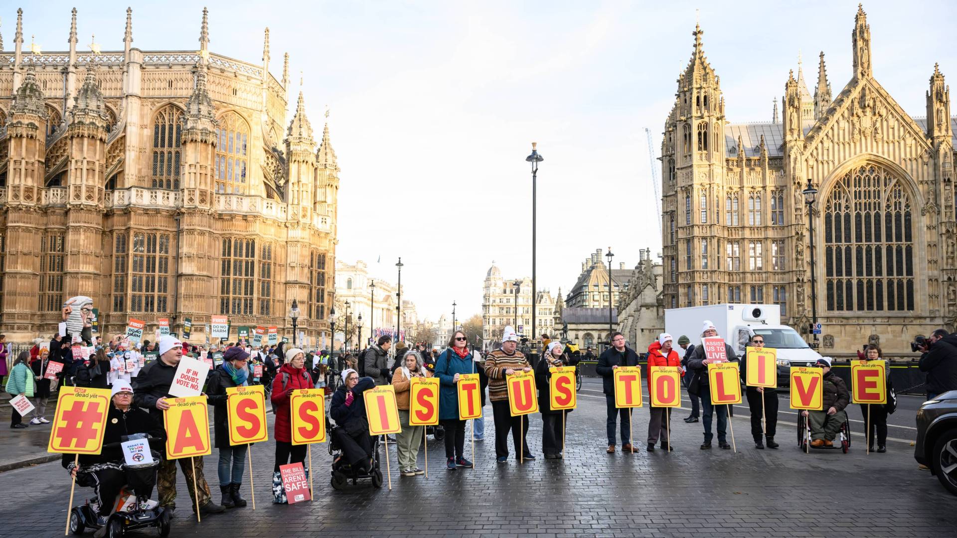 Supporters of the "Not Dead Yet" campaign, which opposes the Assisted Dying Bill, protest outside the Houses of Parliament in London, holding signs that spell out #ASSISTUSTOLIVE.