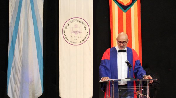 Martin Accad, the new president at Near East School of Theology, speaks at a podium with three school banners behind him