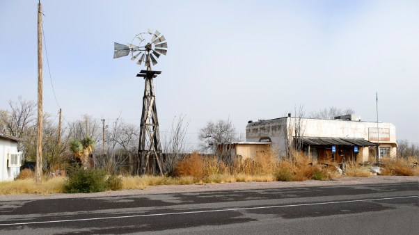 A rundown windmill and building in a desert