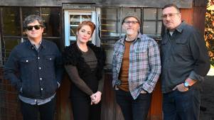 Four members of Sixpence None the Richer, including Leigh Nash, pose for a portrait in front of a barn.