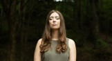portrait of Lindsay Holifield standing in a forrest with her eyes closed