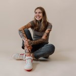 Brenna Blain sitting on the ground of a cream colored background