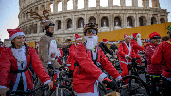 People dressed in Santa costumes on bikes in front of the coleseum